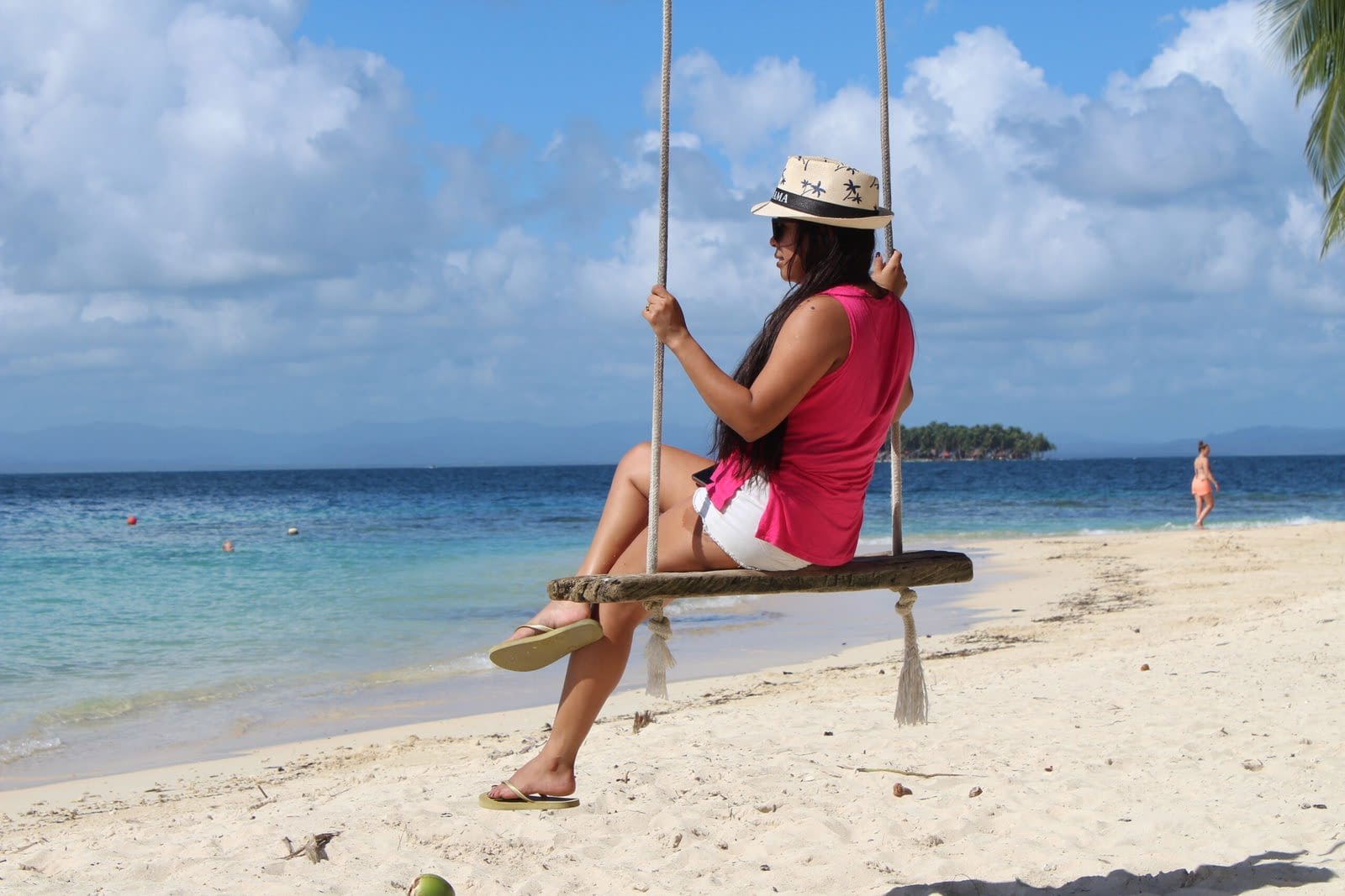 Turista sentada en un columpio colgado de una palmera frente al mar Caribe en las Islas de San Blas, Panamá